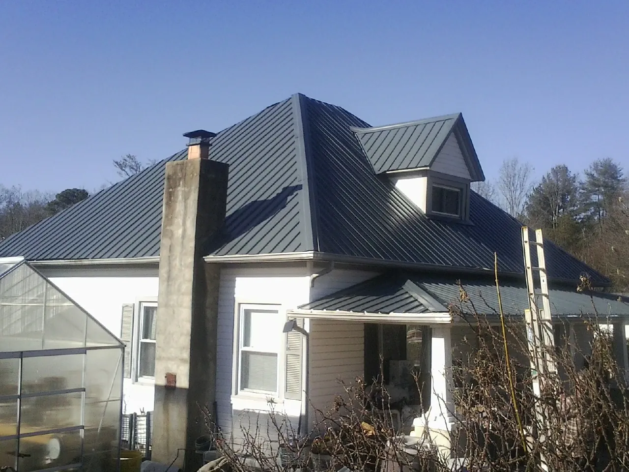 Dark blue standing seam metal roof on a white farmhouse with dormer — Slate & Tile Roof Repair by Roofing Brothers in Gardnerville