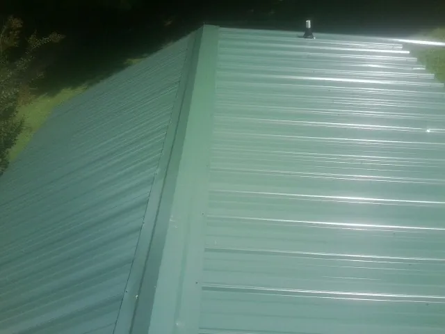 New green metal panels meeting at the ridge of a roof — Flat Roof Repair work by our crew in Gardnerville