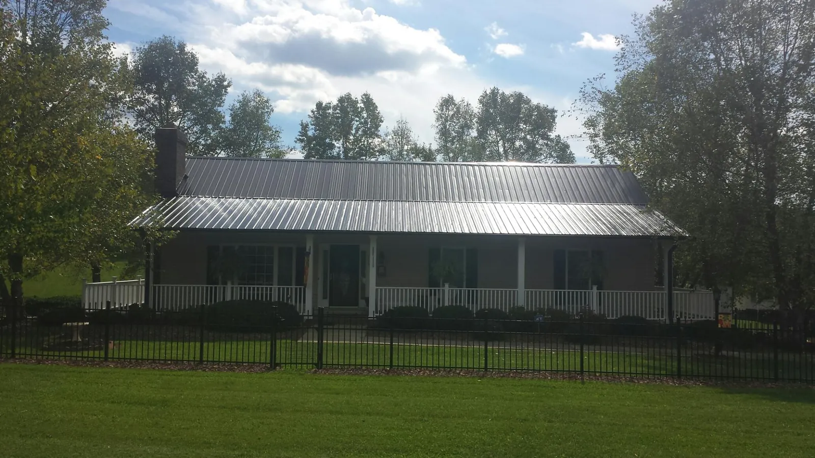 Gray metal roof on a brick ranch with a full width front porch — Gutter Guard Installation work by our crew in Gardnerville