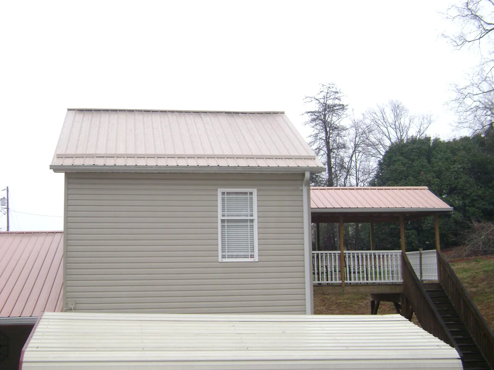 Tan metal roofs on a two story addition and attached porch, from a Roof Replacement job in Gardnerville