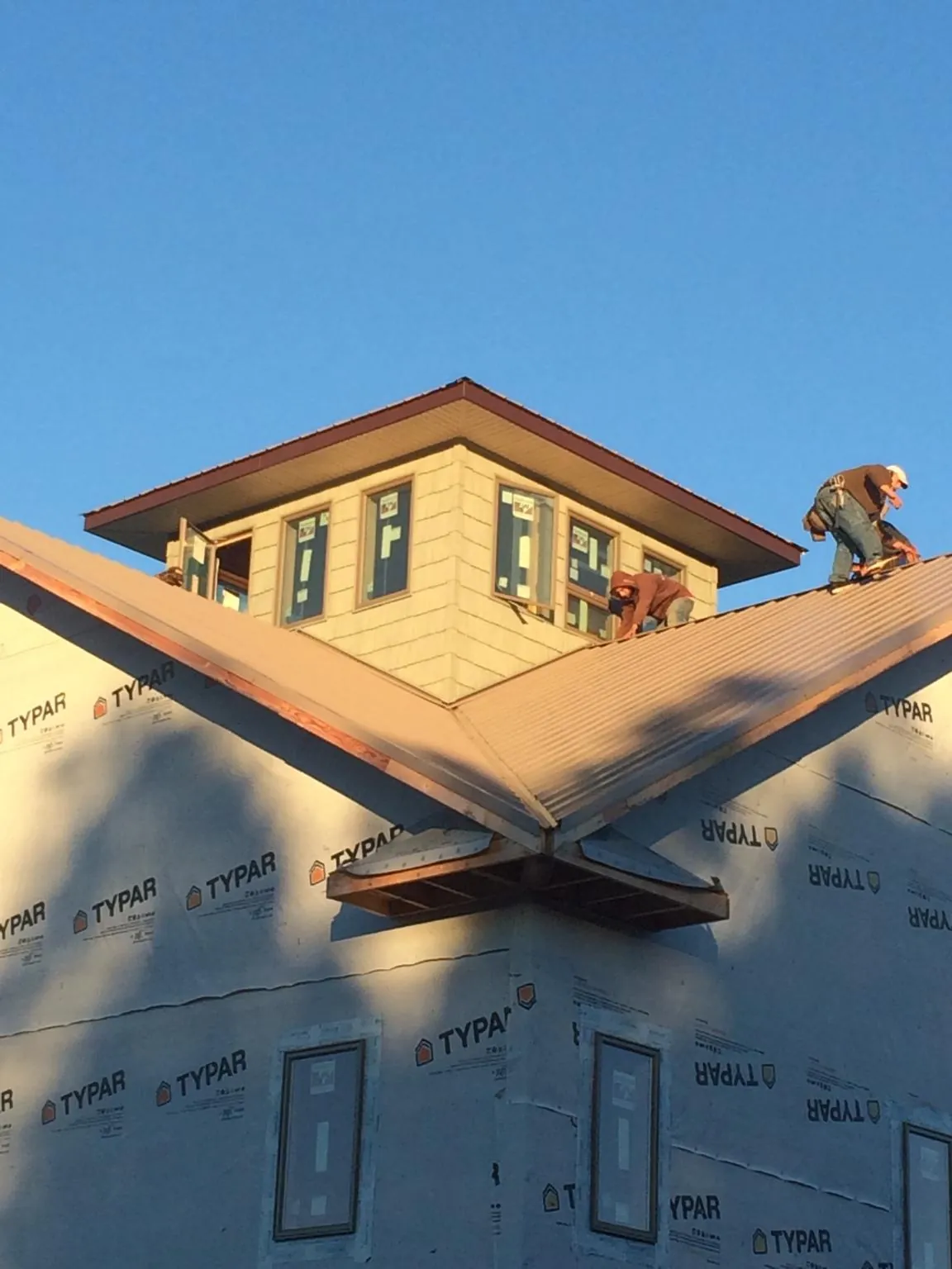 Roofers working around a rooftop cupola on a new metal roof at sunset — Roof Waterproofing in Gardnerville by Roofing Brothers